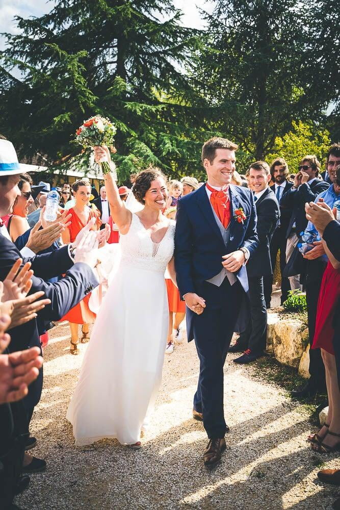 Jeune couple marié marche dans la foule sous le soleil en bourgogne