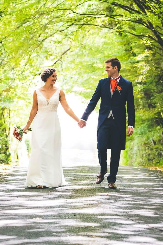 Couple de mariés en robe et queue de pie marche dans la foret 