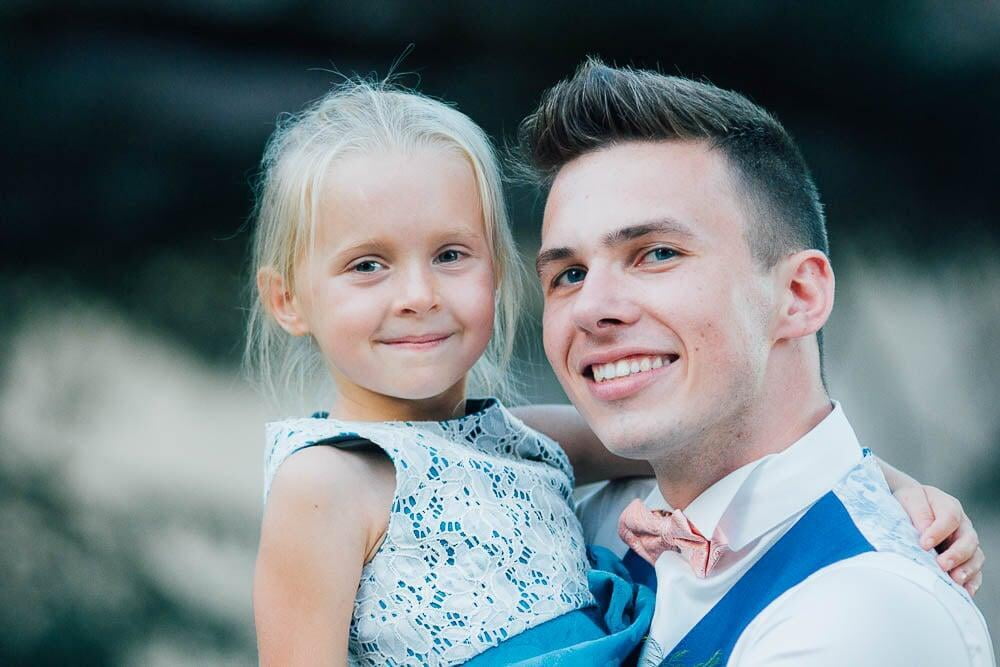 Homme en costume porte sa petite soeur pendant un mariage 